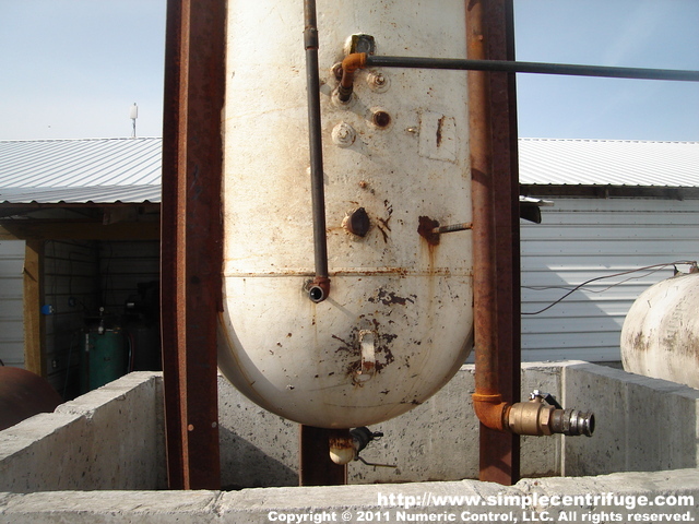 This is the bottom of the vertical tank. The left vertical pipe is the tank vent/over fill pipe. The larger vertical pipe is the fill pipe. Note the cam lock connectors and valve. There is a similar valve and cam lock on the bottom of the tank for draining off water. The horizontal pipe is the feed to the heater and centrifuge. The exit feed is about three feet off the bottom of the tank. This allows the heavier and nastier oil more time to separate and drop more water.