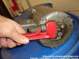 If the parts are REALLY tight you can use a pipe wrench to hold the shaft. No need to remove the motor from the machine. This photo is to demonstrate the process.